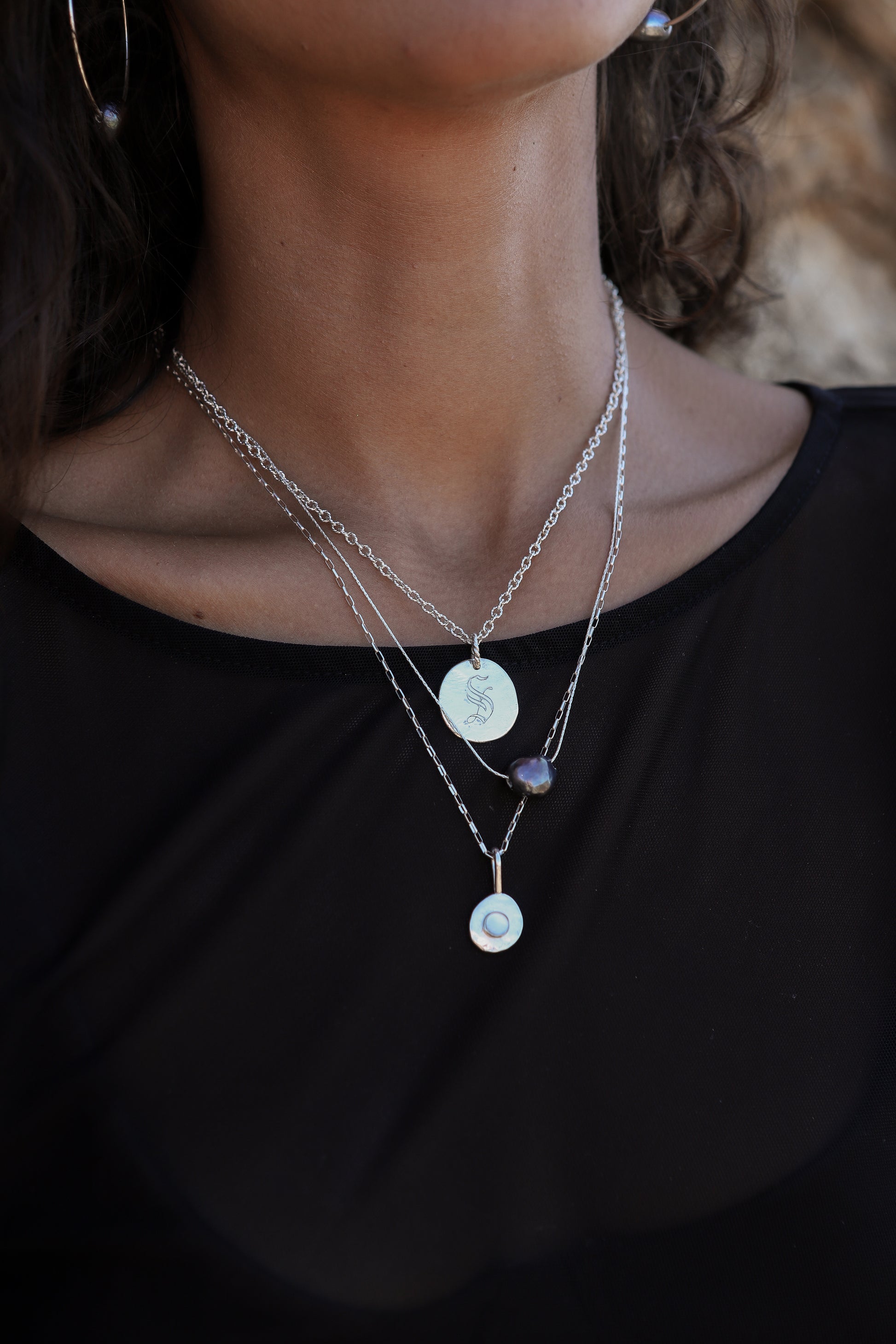 Close-up of a person wearing layered necklaces with pendant details.